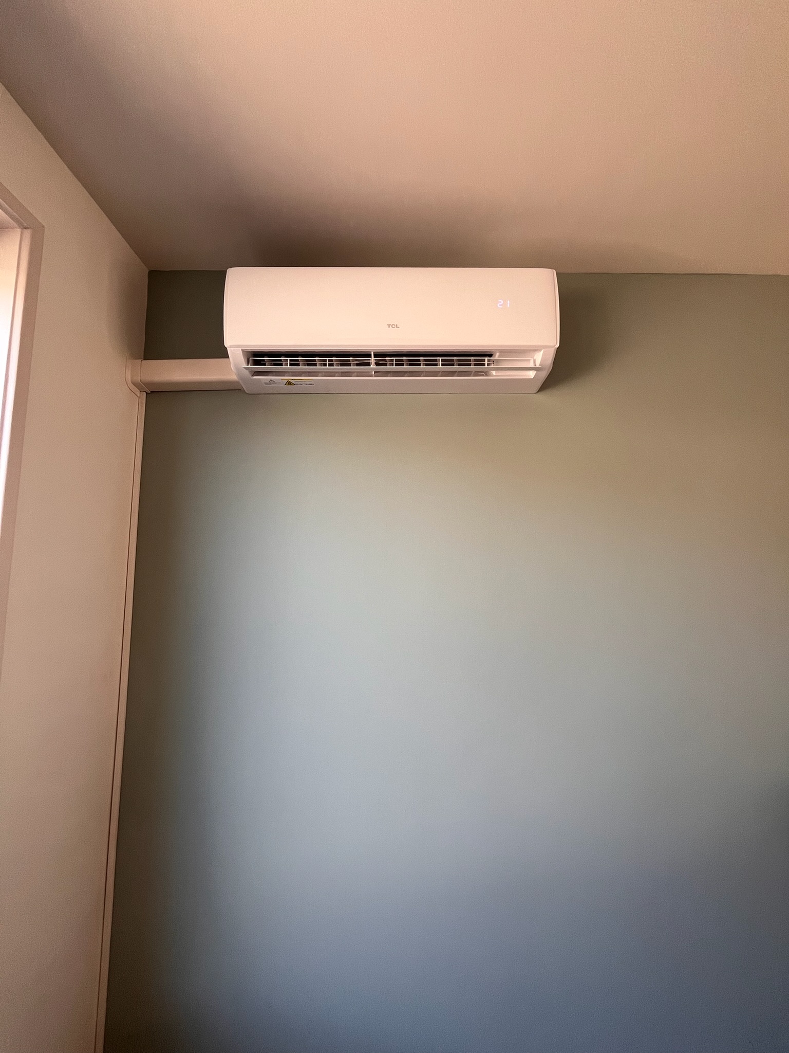 TCL binnenunit — slaapkamer met sage-groene wand